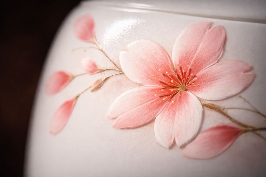 白い陶器の骨壺表面に手描きされた桜の花びらの絵付けを超接写で捉えたマクロ撮影