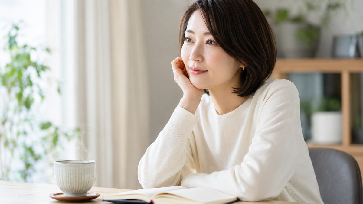 デスクでお茶のそばに座り静かに考えごとをする女性